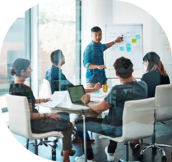 Diverse business team in a conference room collaborating during a whiteboard strategy session, using sticky notes for project planning.