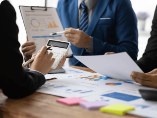 Team of business professionals reviewing financial reports and using a calculator during a corporate strategy discussion.