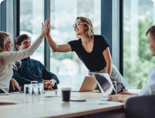 Two business professionals exchanging a high-five during a meeting, representing motivation and successful collaboration.