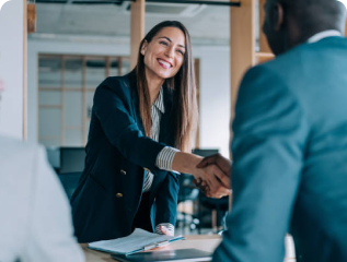 Businesswoman in formal attire smiling and shaking hands with a colleague, symbolizing successful partnership or job interview.