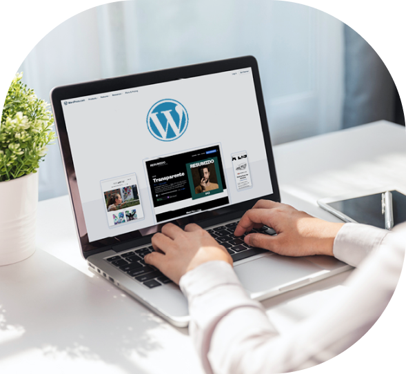 Person designing a WordPress website on a laptop at a clean white desk, showcasing digital content management and web development tools.