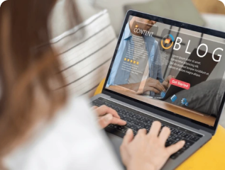 Content creator writing a blog post on a laptop with a modern blog interface on screen, seated comfortably at home
