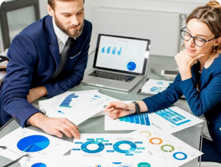 Business professionals analyzing financial and marketing data charts at a desk with laptops and printed analytics reports