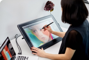 Female artist using a pen display tablet to create a vibrant digital portrait, emphasizing illustration, creativity, and digital painting