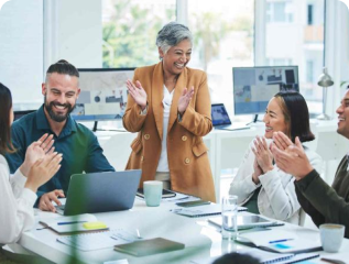 Diverse business team celebrating success with applause in a bright office environment, led by a smiling senior manager.
