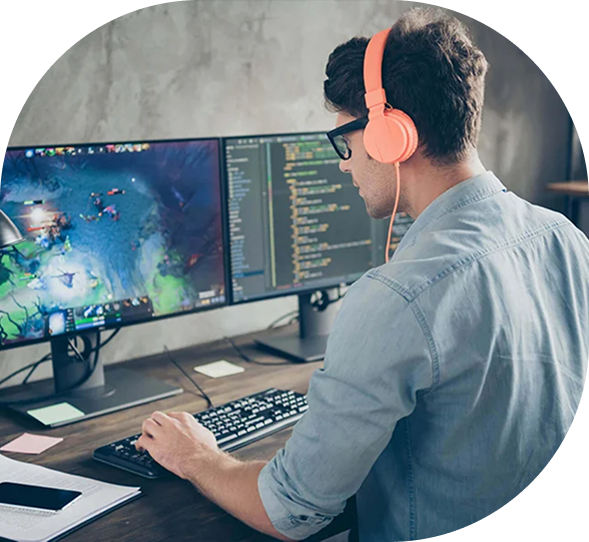 Game developer coding and testing video game on dual monitors with code editor and gameplay visuals – game programming workspace.